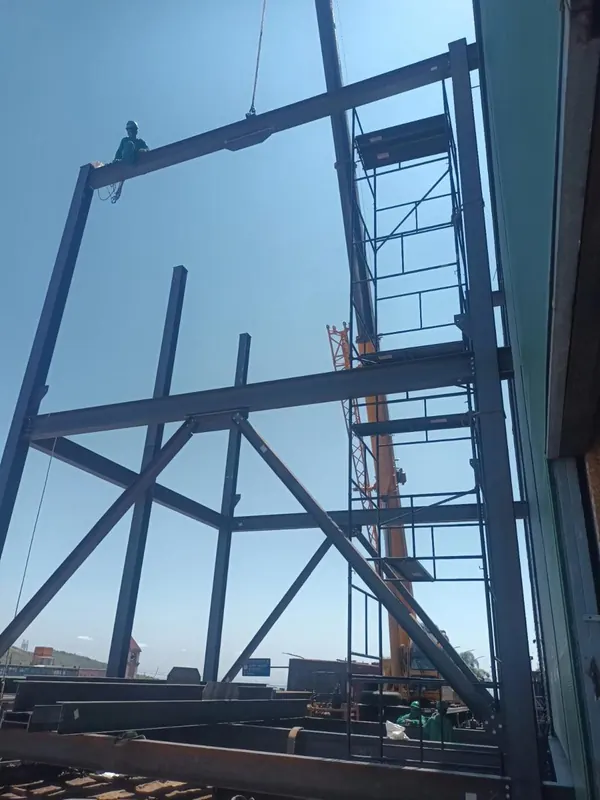 Montador no alto da estrutura do elevador de carga durante o içamento de uma viga
