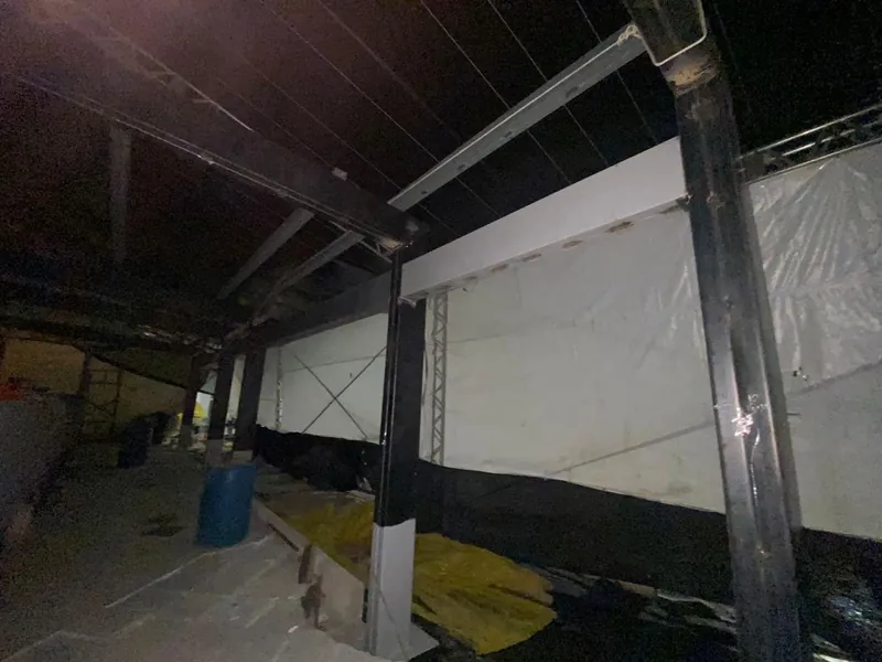 Pilares e vigas da estrutura à noite, junto à lona de proteção