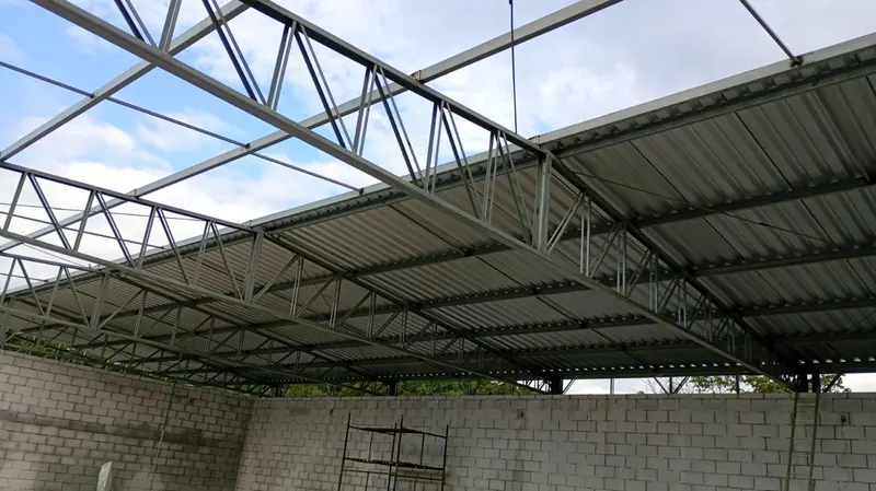 Telhas sendo instaladas sob as treliças da cobertura