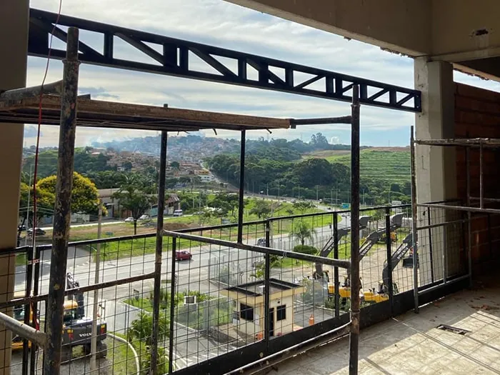 Treliça metálica escura da cobertura da escada, com guarda-corpo e vista da rodovia