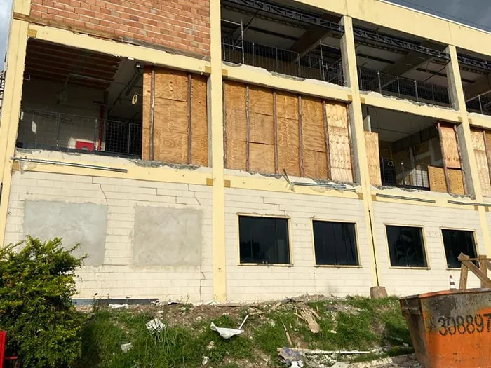 Fachada do prédio em obra, com aberturas fechadas por tapumes