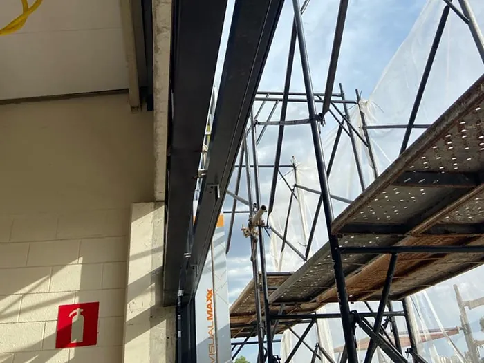 Pilar metálico da escada e andaime com plataforma metálica junto à parede