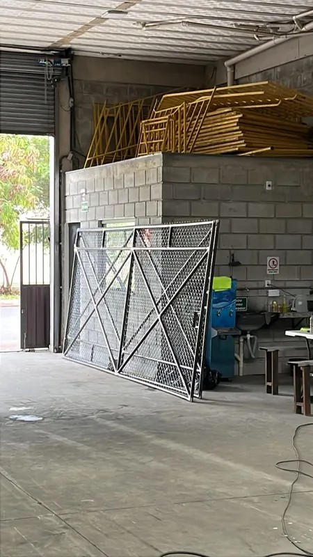 Portão tubular com tela concluído, encostado na parede da fábrica