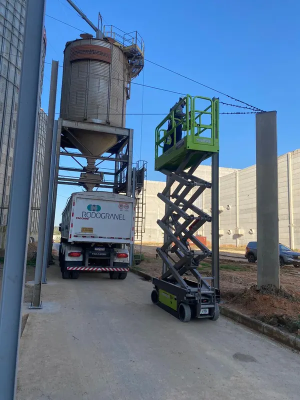 Montador em plataforma elevatória fixando a estrutura ao lado do silo